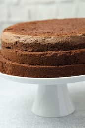 Photo of Cut chocolate sponge cake on light table, closeup