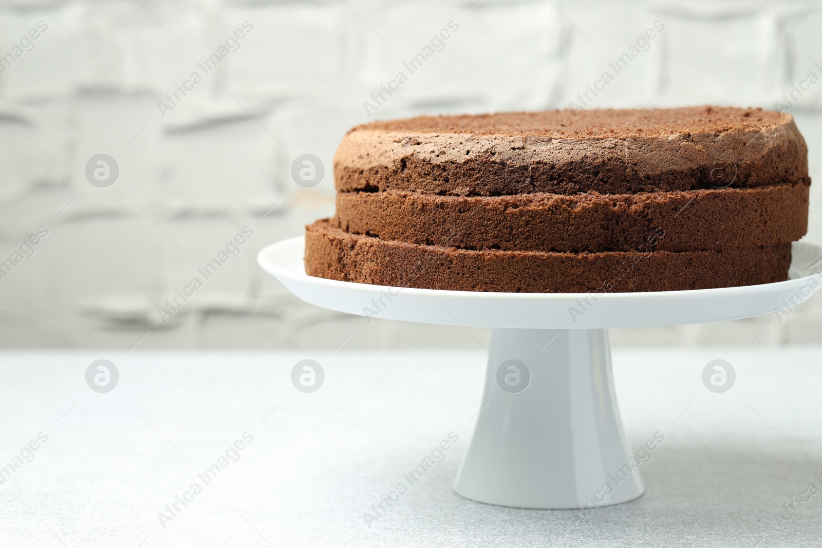 Photo of Cut chocolate sponge cake on light table, closeup