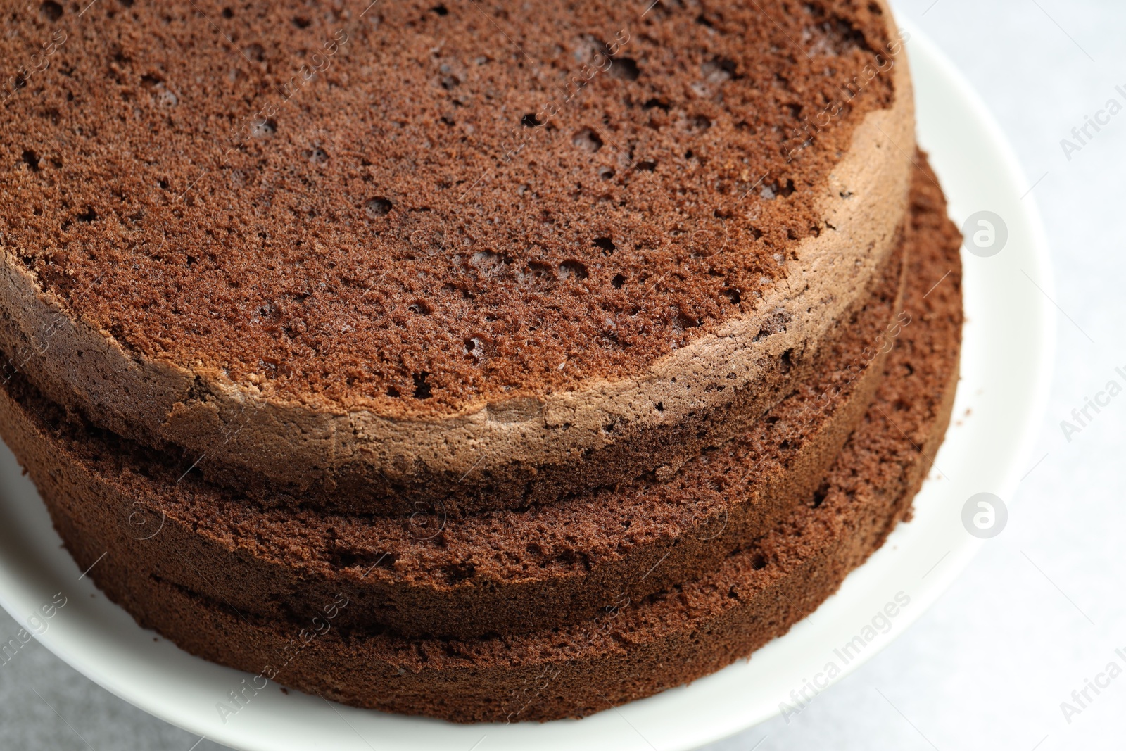 Photo of Cut chocolate sponge cake on light table, closeup