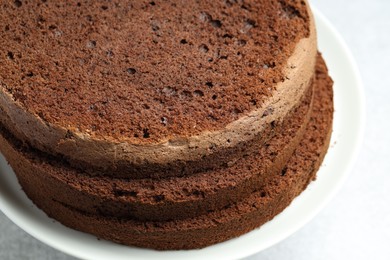 Photo of Cut chocolate sponge cake on light table, closeup