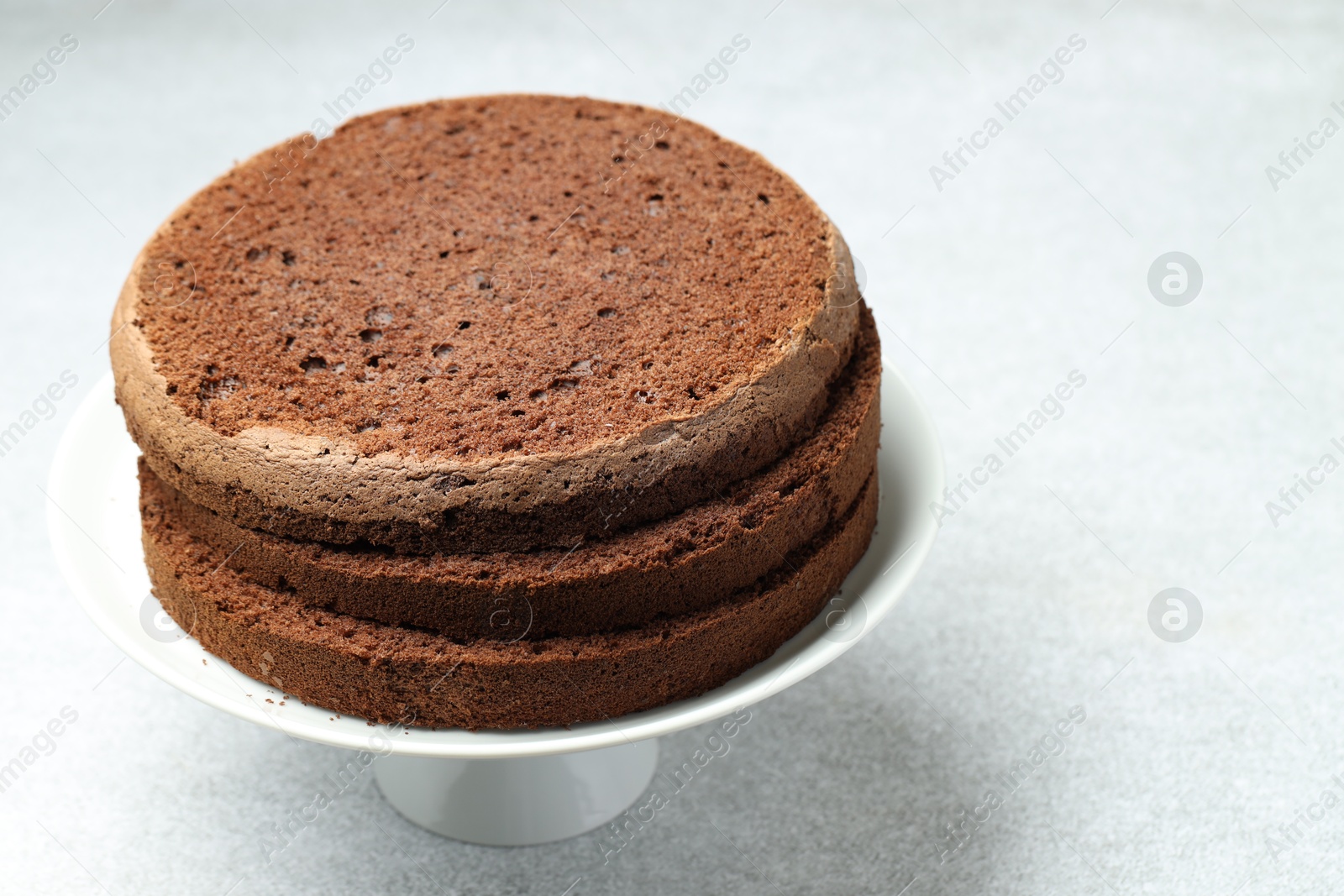 Photo of Cut chocolate sponge cake on light table, closeup