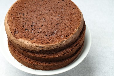 Photo of Cut chocolate sponge cake on light table, closeup