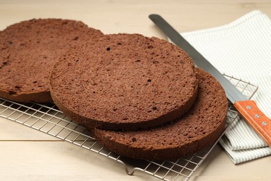 Photo of Cut tasty chocolate sponge cake and knife on wooden table, closeup