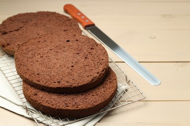 Photo of Cut tasty chocolate sponge cake and knife on wooden table, closeup