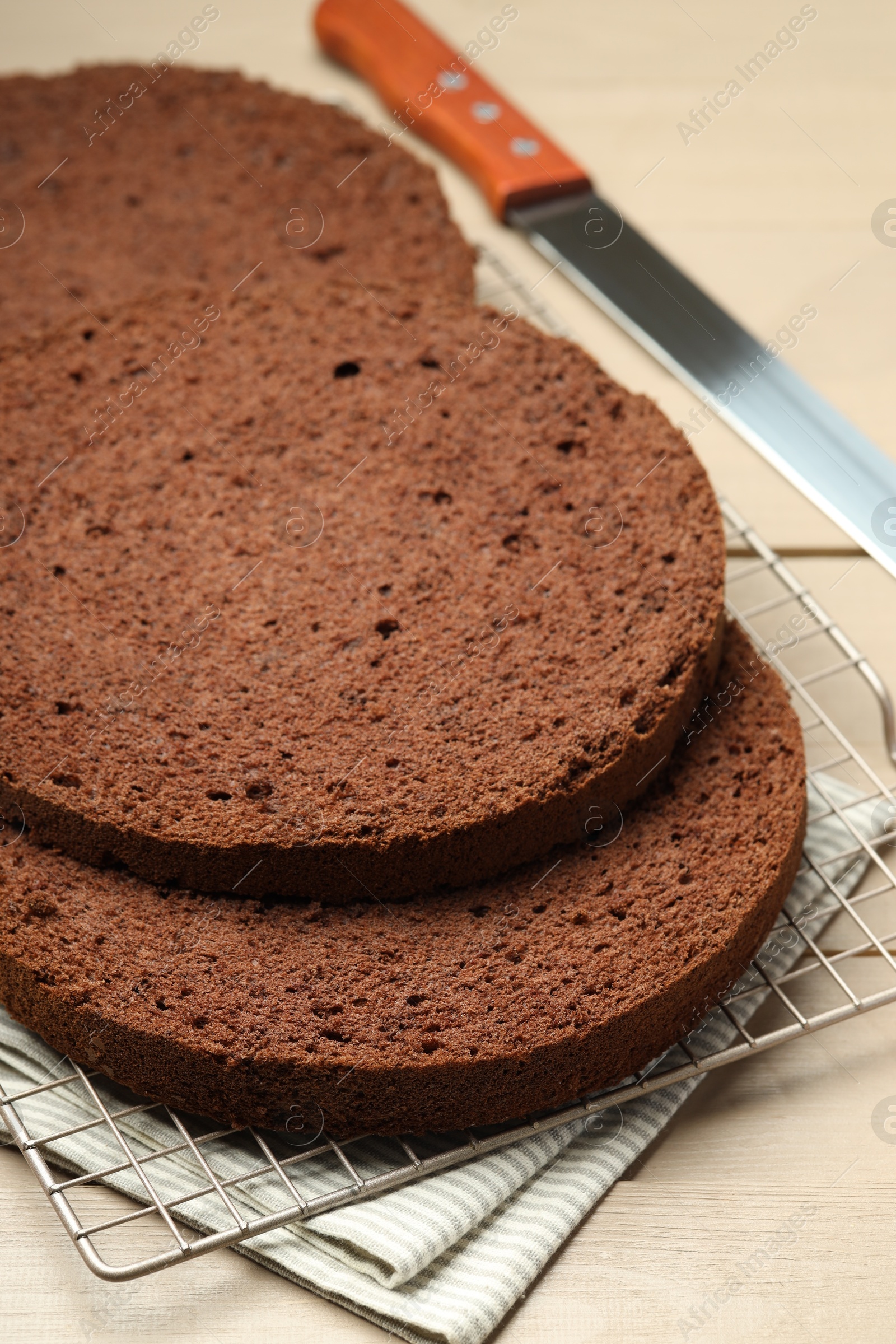 Photo of Cut tasty chocolate sponge cake and knife on wooden table, closeup