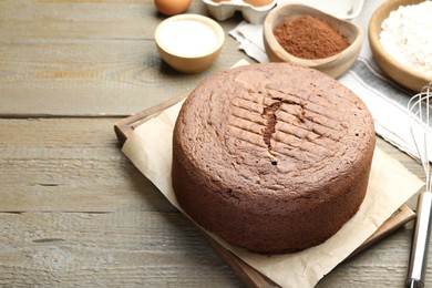 Photo of Tasty chocolate sponge cake and ingredients on wooden table