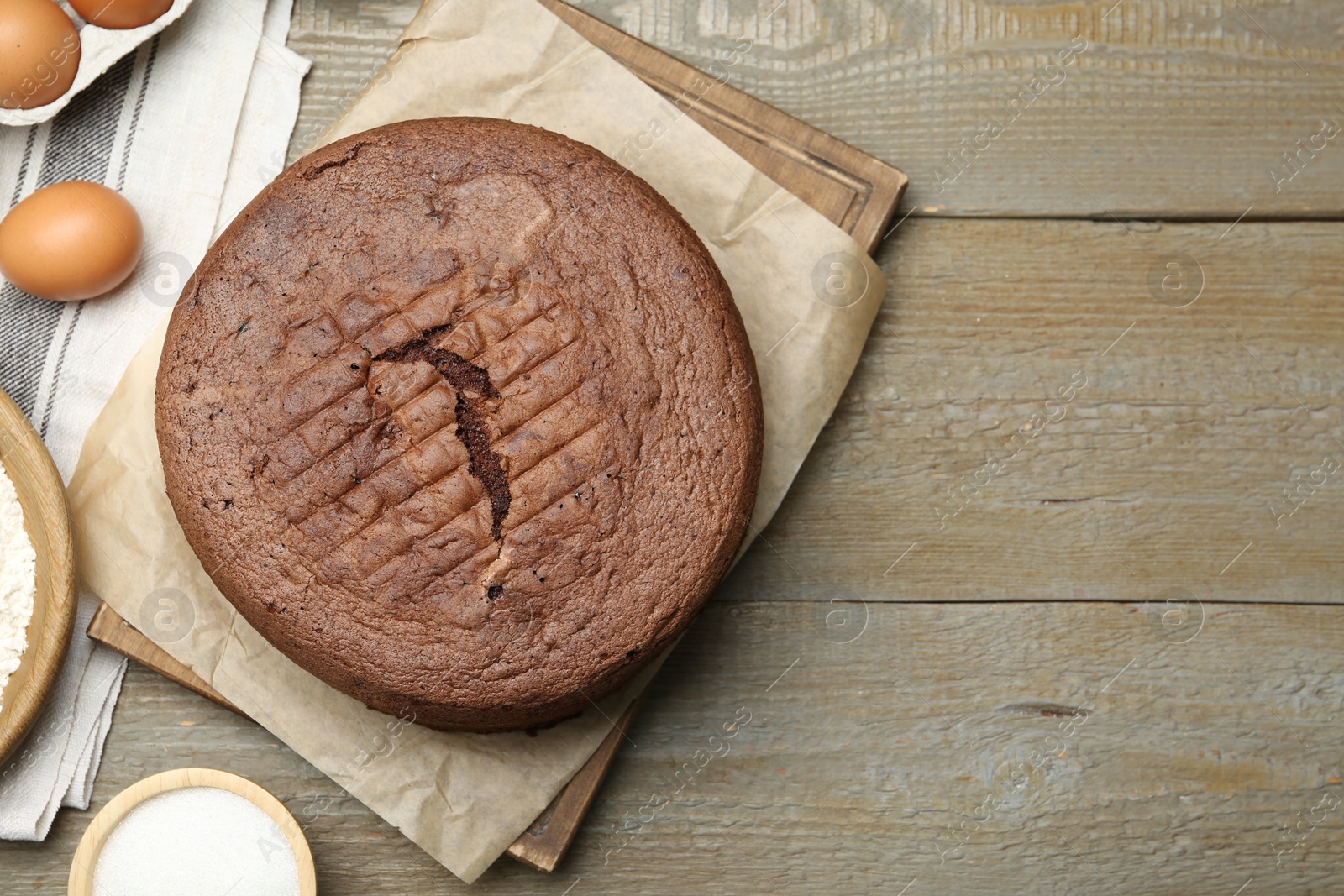 Photo of Tasty chocolate sponge cake and ingredients on wooden table, flat lay. Space for text