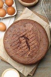 Photo of Tasty chocolate sponge cake and ingredients on wooden table, flat lay