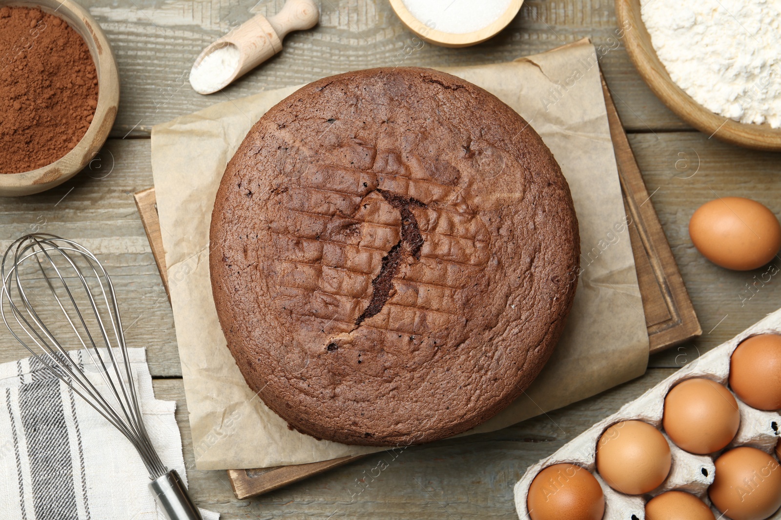 Photo of Tasty chocolate sponge cake and ingredients on wooden table, flat lay