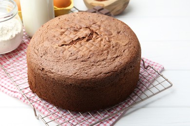 Photo of Tasty chocolate sponge cake and ingredients on white wooden table, closeup