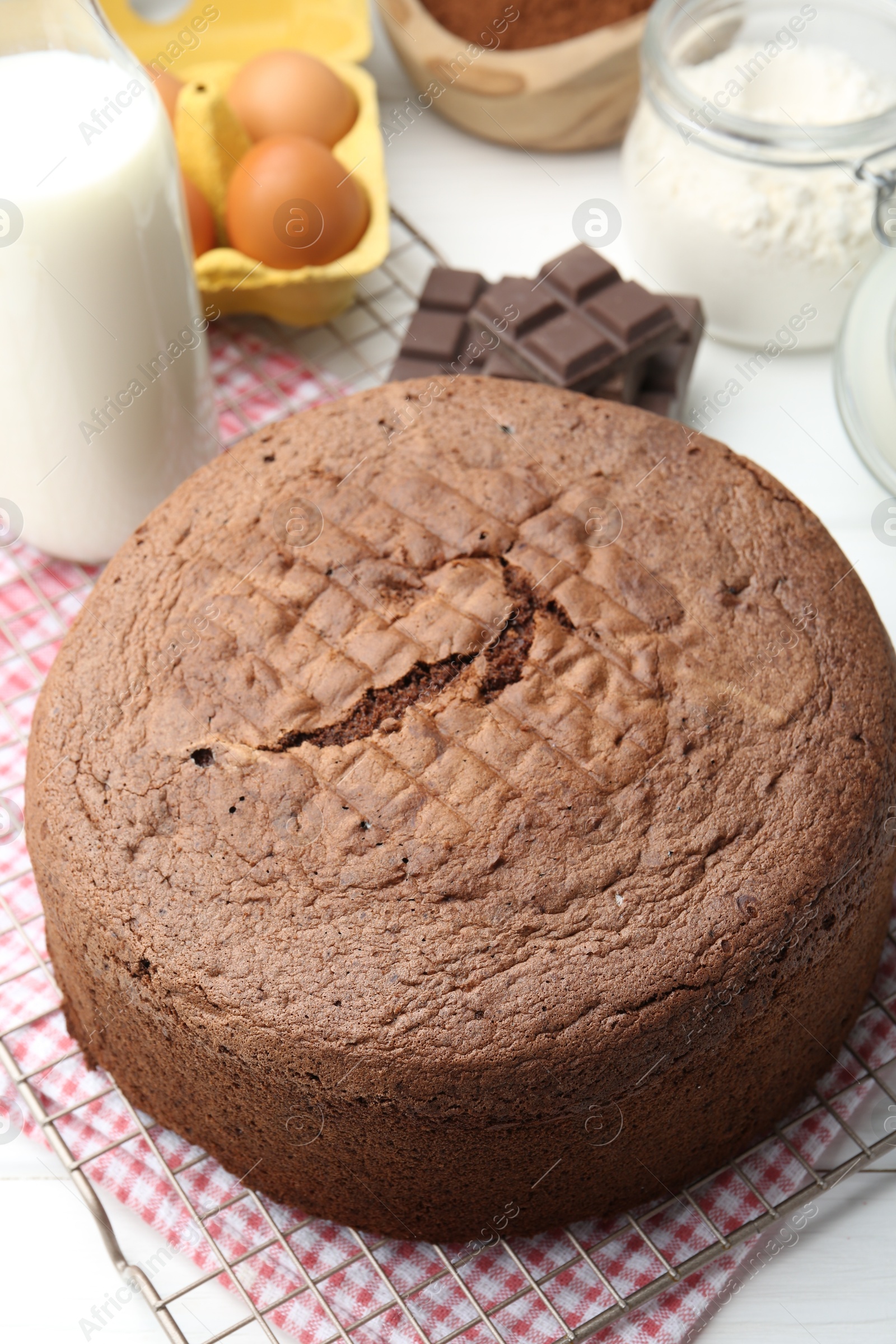 Photo of Tasty chocolate sponge cake and ingredients on white wooden table, closeup