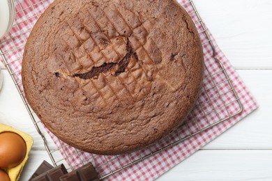 Photo of Tasty chocolate sponge cake on white wooden table, top view