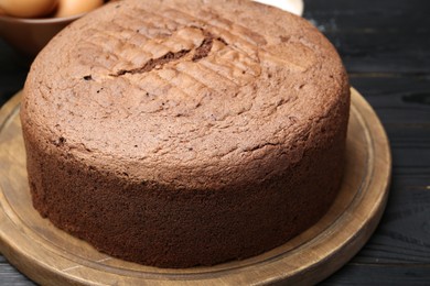 Photo of Tasty chocolate sponge cake on black wooden table, closeup