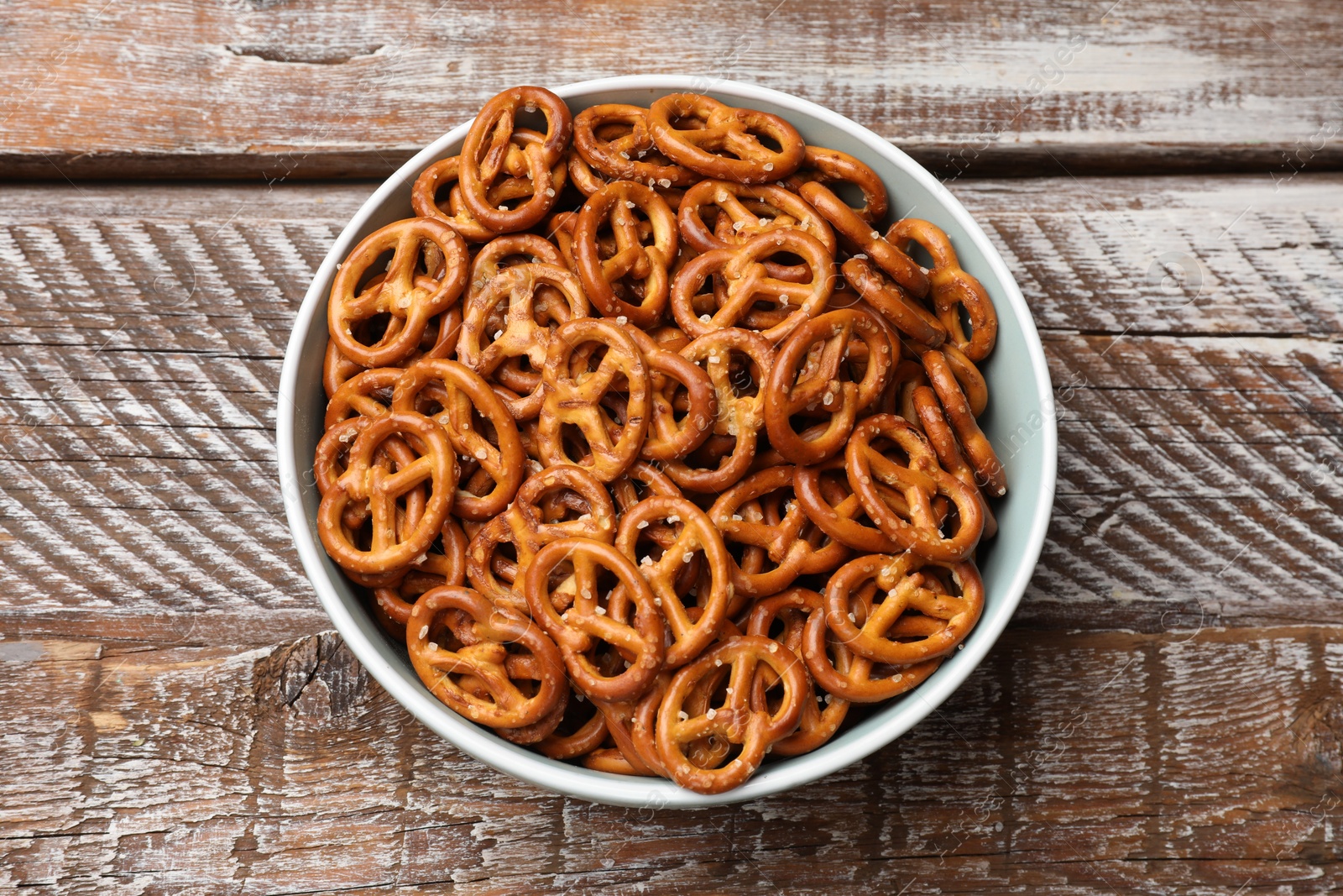 Photo of Delicious salty pretzel crackers on wooden table, top view