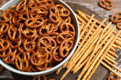 Photo of Delicious pretzel crackers and salty sticks on wooden table, above view