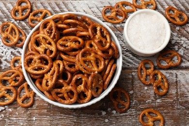 Photo of Delicious pretzel crackers and sea salt on wooden table, flat lay