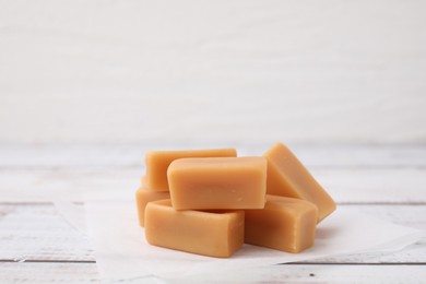 Photo of Tasty sweet caramel candies on white wooden table, closeup