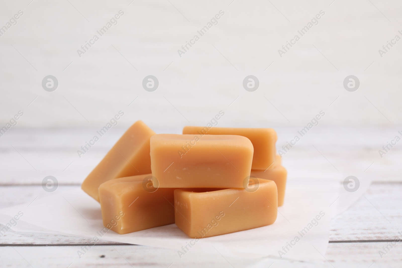 Photo of Tasty sweet caramel candies on white wooden table, closeup