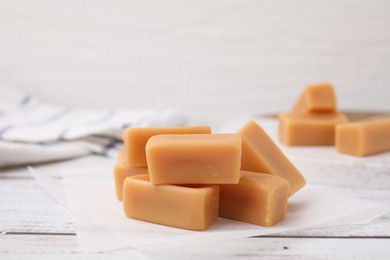 Photo of Tasty sweet caramel candies on white wooden table, closeup