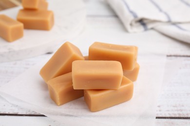 Photo of Tasty sweet caramel candies on white wooden table, closeup