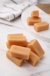 Photo of Tasty sweet caramel candies on white table, closeup