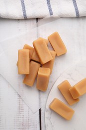 Photo of Tasty sweet caramel candies on white wooden table, flat lay