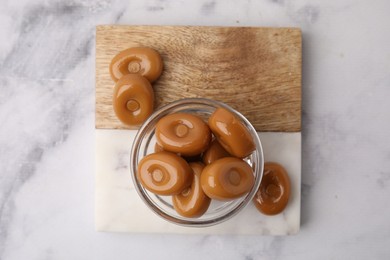 Photo of Tasty hard toffee candies on white marble table, top view