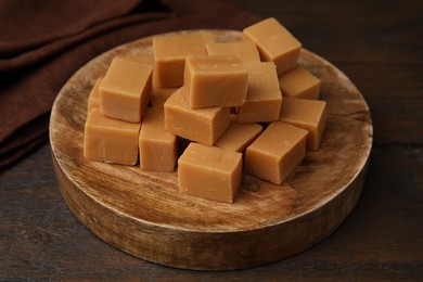 Photo of Tasty sweet caramel candies on wooden table, closeup