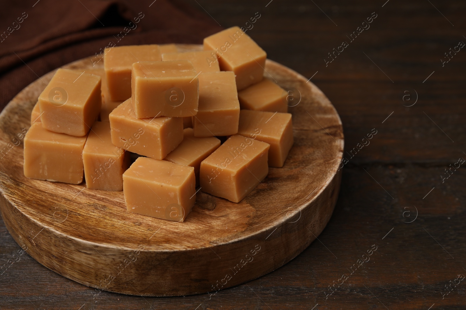 Photo of Tasty sweet caramel candies on wooden table, closeup