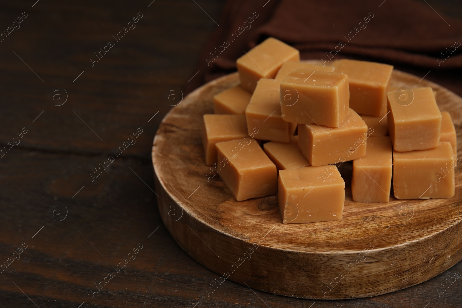 Photo of Tasty sweet caramel candies on wooden table, closeup. Space for text