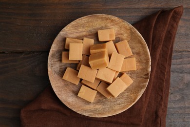 Photo of Tasty sweet caramel candies on wooden table, top view