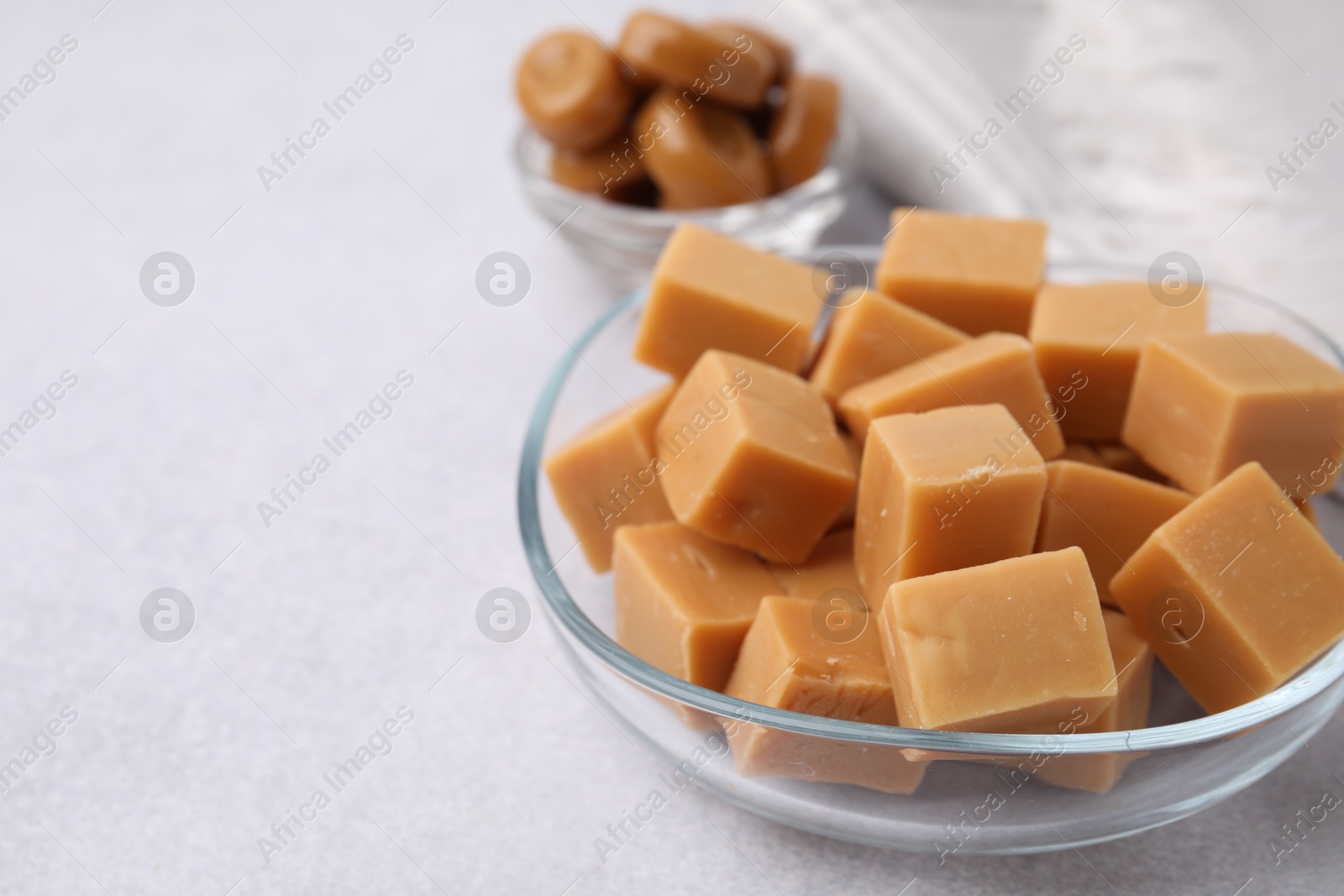 Photo of Tasty sweet caramel candies on light grey table, closeup. Space for text