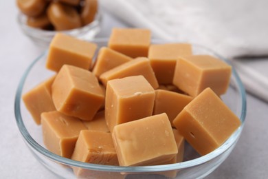 Photo of Tasty sweet caramel candies in bowl on light table, closeup