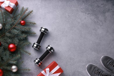 Photo of Dumbbells, gift boxes, fitness mat, sneakers and Christmas decor on grey background, flat lay. Space for text