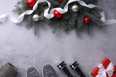 Photo of Dumbbells, gift box, fitness mat, sneakers and Christmas decor on grey background, flat lay. Space for text