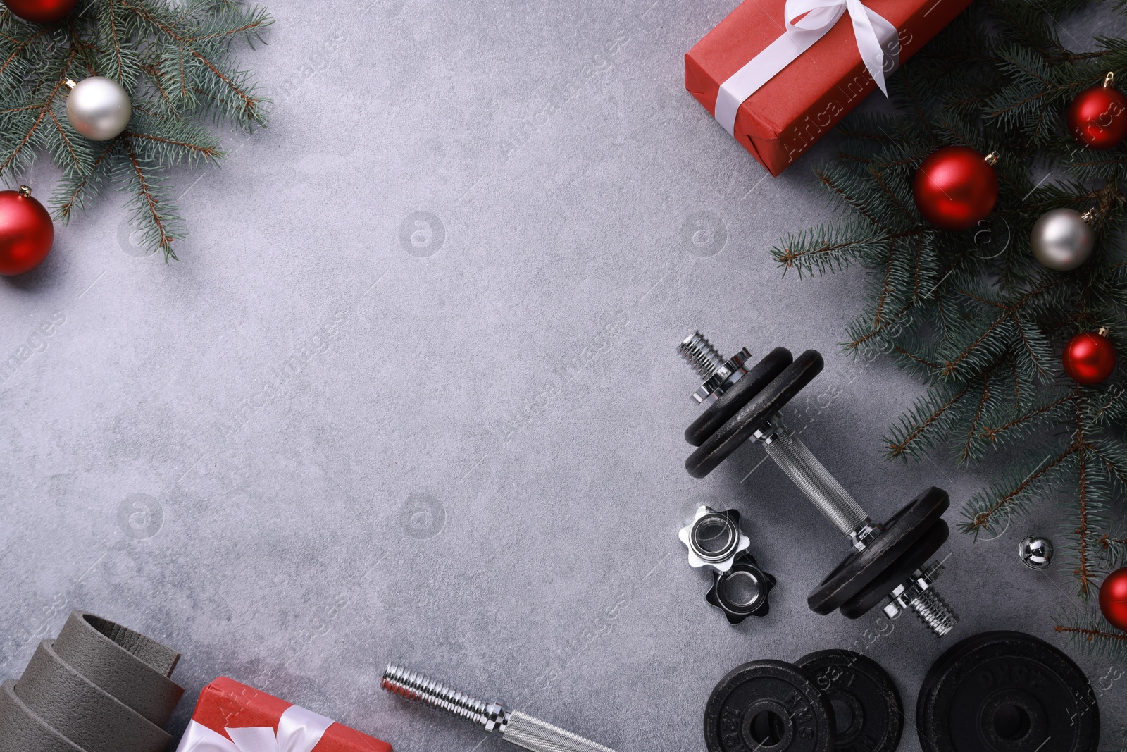 Photo of Barbell, gift boxes, fitness mat and Christmas decor on grey background, flat lay. Space for text