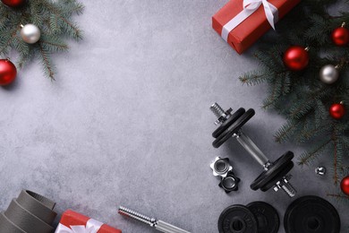 Photo of Barbell, gift boxes, fitness mat and Christmas decor on grey background, flat lay. Space for text