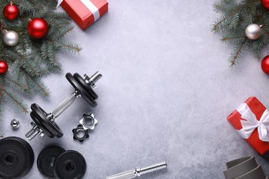 Photo of Barbell, gift boxes, fitness mat and Christmas decor on grey background, flat lay. Space for text