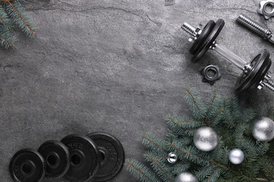 Photo of Barbell, dumbbell parts and Christmas decor on grey background, flat lay. Space for text