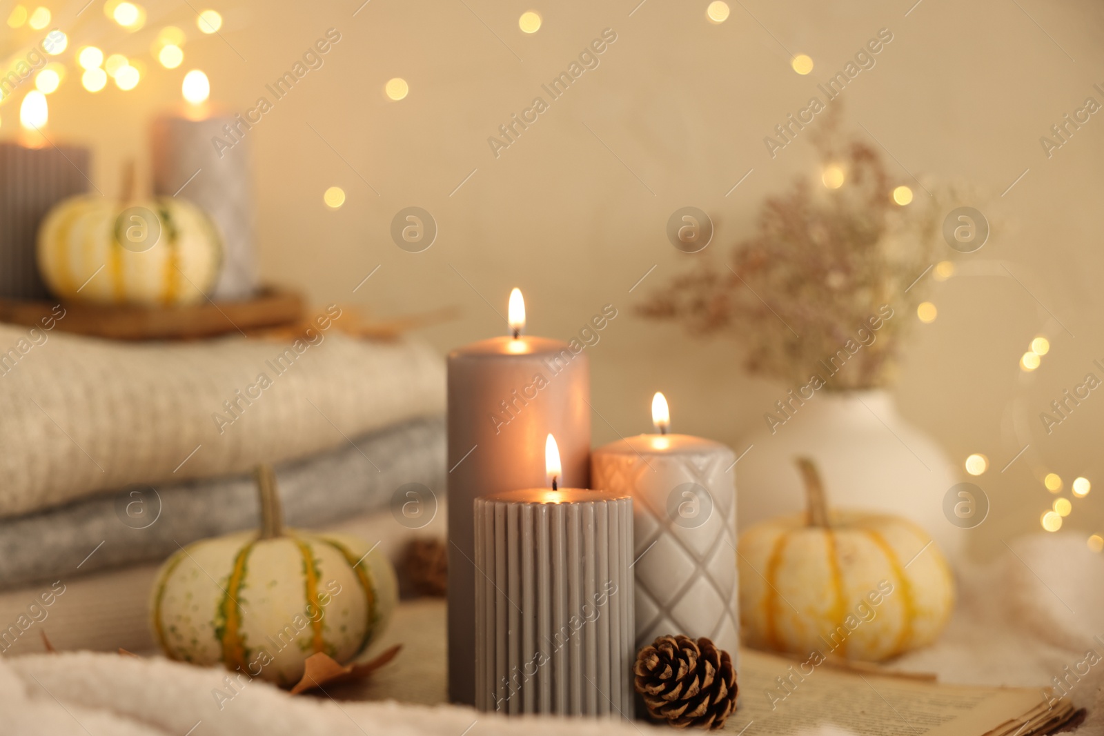 Photo of Burning candles, pumpkins and cone indoors. Autumn atmosphere