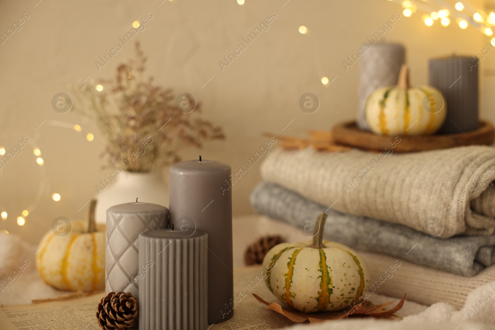 Photo of Grey candles and autumn decor indoors, closeup