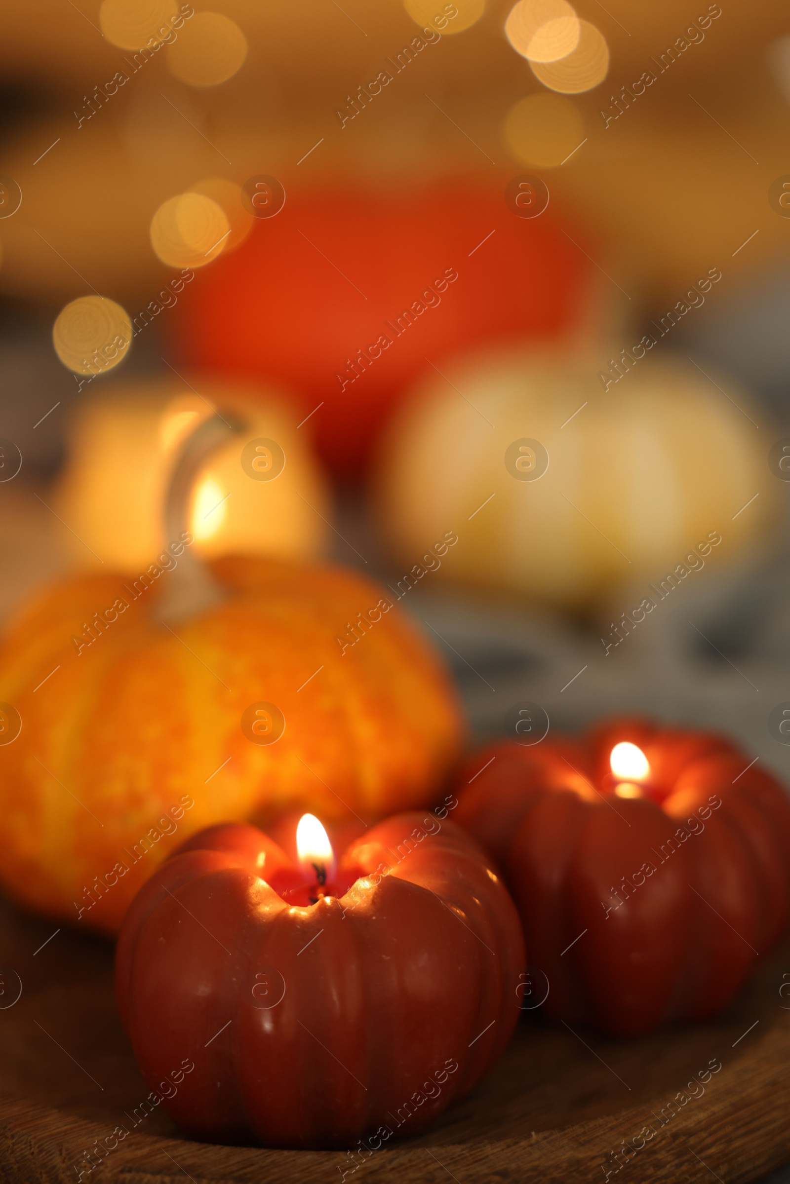 Photo of Burning candles and pumpkin against blurred lights, closeup. Autumn atmosphere