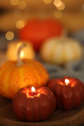 Photo of Burning candles and pumpkin against blurred lights, closeup. Autumn atmosphere