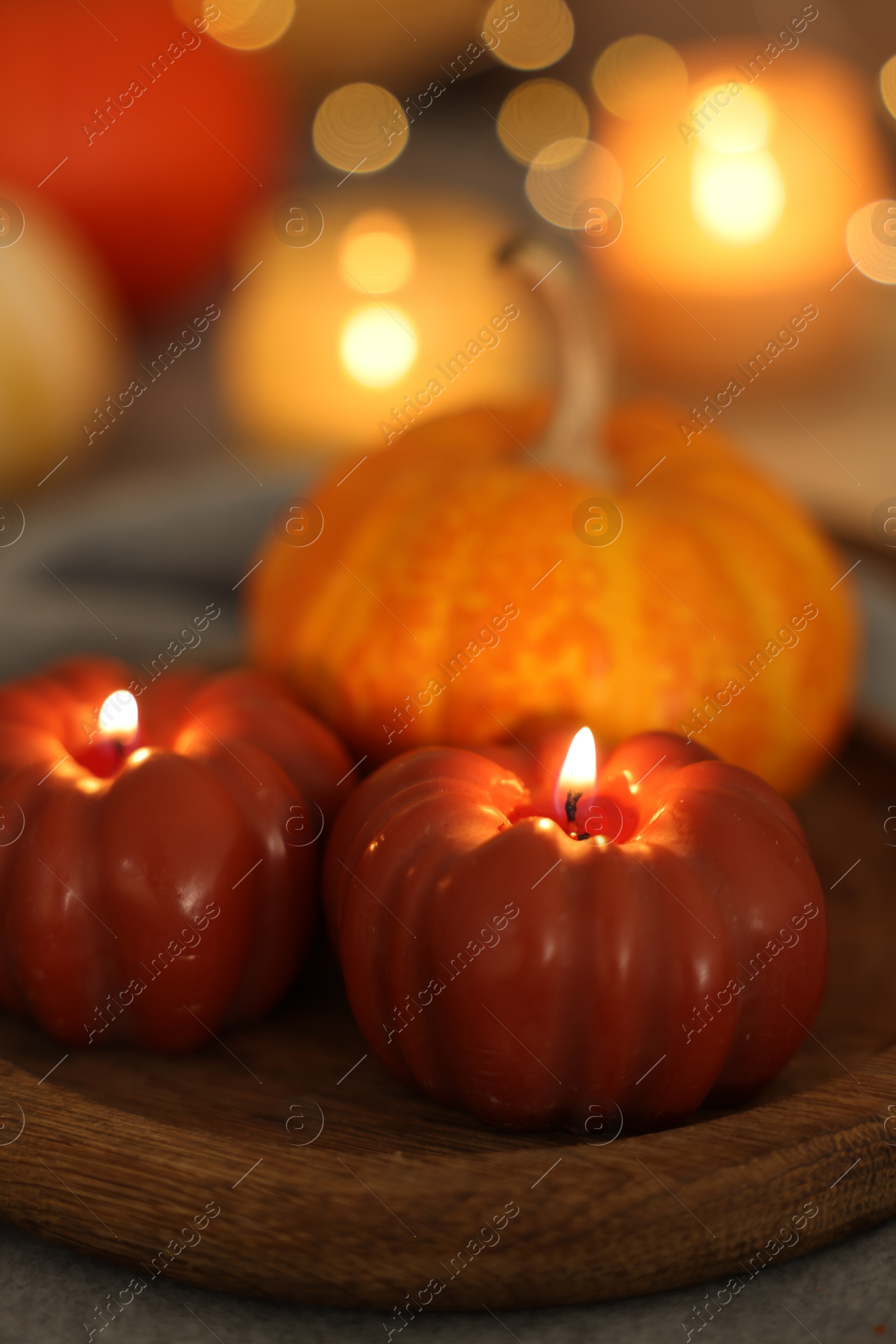 Photo of Burning candles and pumpkin against blurred lights, closeup. Autumn atmosphere