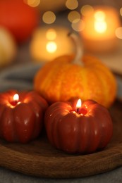 Photo of Burning candles and pumpkin against blurred lights, closeup. Autumn atmosphere