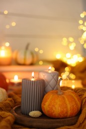 Photo of Burning candles and pumpkin on soft sweater indoors, space for text. Autumn atmosphere