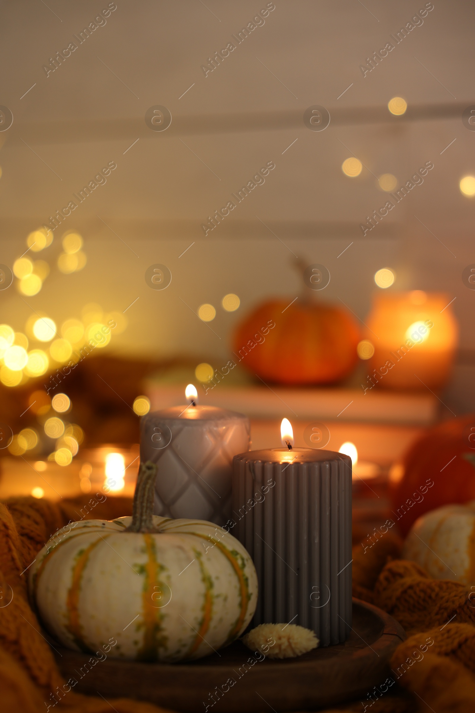 Photo of Burning candles and pumpkin on soft sweater indoors, space for text. Autumn atmosphere