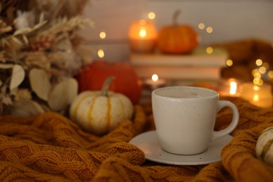 Photo of Cup of coffee on soft sweater, space for text. Autumn atmosphere