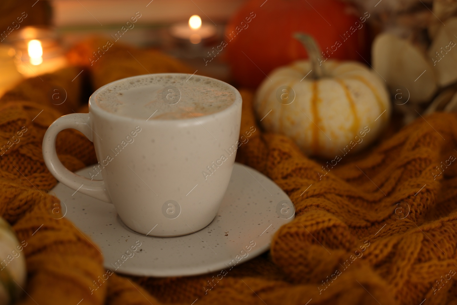 Photo of Cup of coffee on soft sweater, closeup. Autumn atmosphere