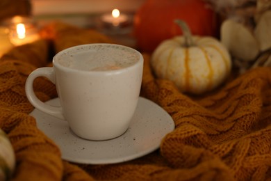 Photo of Cup of coffee on soft sweater, closeup. Autumn atmosphere